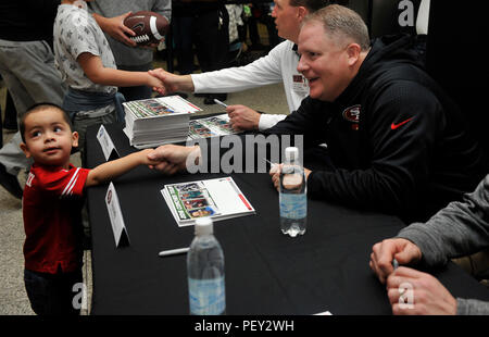 Chip Kelly, San Francisco 49ers head coach, scuote le mani con un giovane ventola durante un incontrare e salutare per il 2016 Pullman Tour di Febbraio 14, 2016 a Ramstein Air Base, Germania. Appassionati hanno avuto la possibilità di incontrare e parlare con e ottenere autografi da quattro pullman da entrambi la collegiata e le leghe professionistiche. (U.S. Air Force foto/Airman 1. Classe Larissa Greatwood) Foto Stock