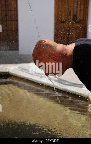 Un turista in Spagna si raffredda a una fontana di acqua. Foto Stock