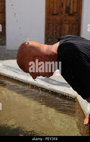 Un turista in Spagna si raffredda a una fontana di acqua. Foto Stock