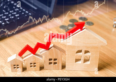 Una freccia rossa sopra il case di legno. Concetto di aumentare la domanda e offerta nel mercato immobiliare. Aumento dei costi e dei prezzi delle case, b Foto Stock