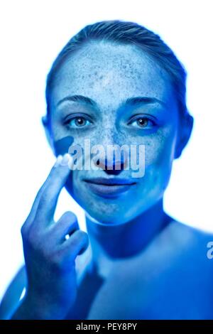 Donna l'applicazione di crema solare alla sua guancia. Foto Stock