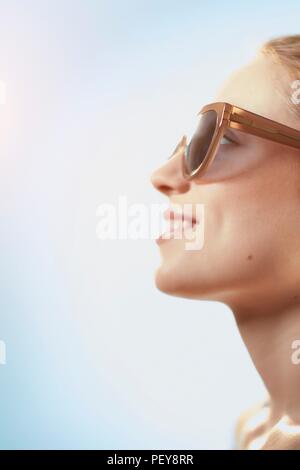 Donna che indossa gli occhiali da sole, sorridente. Foto Stock
