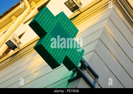 Farmacia segno con LED verde sulla parete di facciata durante il dolce Tramonto Foto Stock