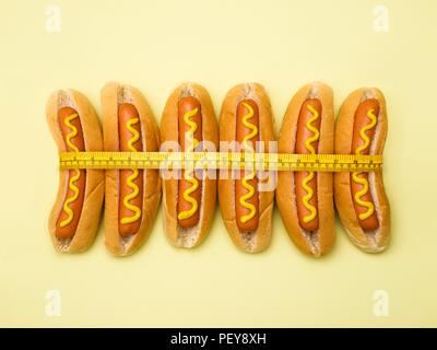 Dieta, immagine concettuale. Nastro di misurazione intorno hot dogs. Foto Stock