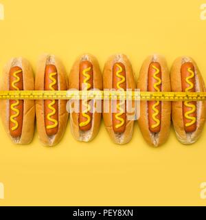 Dieta, immagine concettuale. Nastro di misurazione intorno hot dogs. Foto Stock