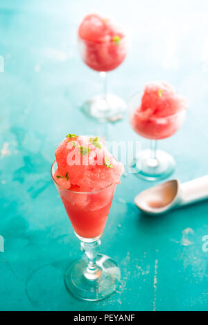 Granita Warermelon su un piccolo bicchiere sopra uno sfondo blu con focus tecnica selettiva Foto Stock