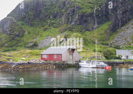 Casa vicino a bordo di acqua con barche ormeggiate su una piccola isola norvegese. Foto Stock