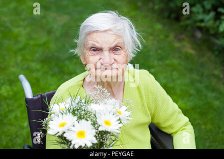 Donna anziana affetti da demenza malattia ricezione di fiori per la sua festa di compleanno Foto Stock