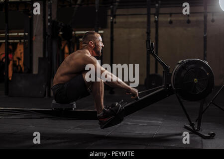 Ambizioso sportivo è il training su indoor rower con tutte le sue forze.La forza di volontà concept.professional sport Foto Stock