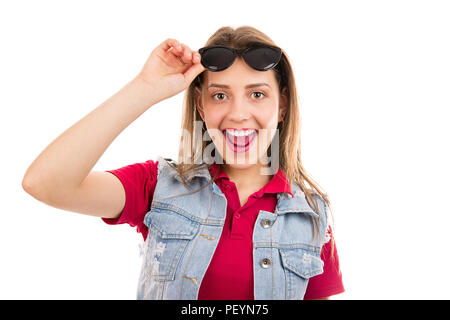 Allegro giovane donna graziosa in occhiali da sole e giubbotto in denim cercando felicemente in telecamera isolata su sfondo bianco Foto Stock