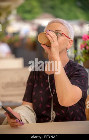 Una donna assetata è di bere il caffè nero all'esterno. Il concetto di bevande Foto Stock