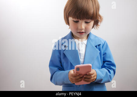 Ragazzo intelligente è texting messaggio, giocando giochi ponline., l'invio di immagini, download di musica, film. boy è di imparare a utilizzare il telefono cellulare Foto Stock