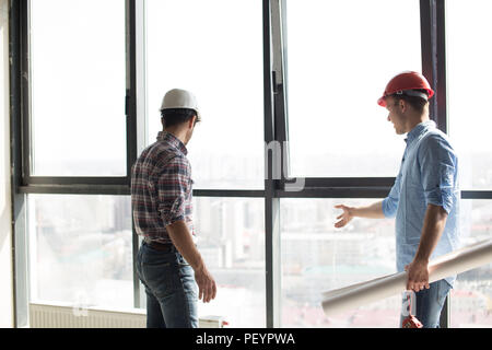 Due costruttori stanno controllando il nuovo panorama windows in un edificio per uffici Foto Stock