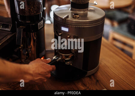 Un uomo sta andando a preparare il caffè macinato fresco. maschio di contenimento della polvere di caffè Foto Stock