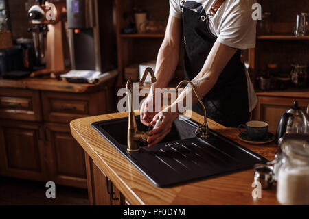 Ritratto di giovane cameriere di lavarsi le mani in cucina presso il cafe. close up foto ritagliata Foto Stock