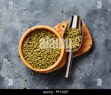 Verde fagioli mung in ciotola di legno su uno sfondo grigio. Vista dall'alto di semole. Foto Stock