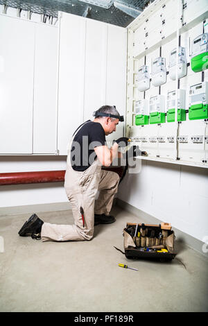 Elettricista con la cassetta degli attrezzi di fissaggio scatola dei fusibili o scatola di commutazione Foto Stock