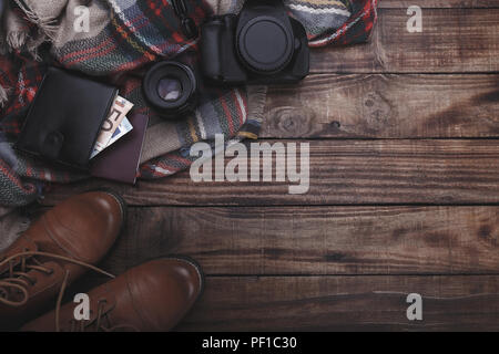 Traveler del fotografo accessori della lente della fotocamera stivali thermos portamonete con denaro plaid e notepad sul vecchio fienile Sfondo legno Foto Stock