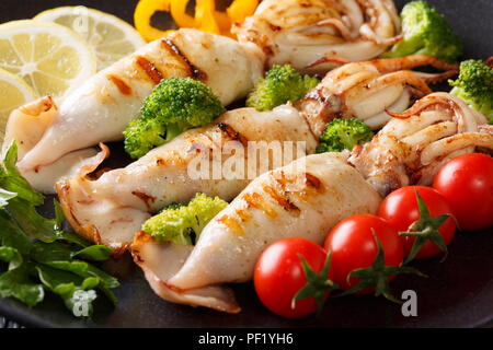 Calamari alla griglia con verdure fresche di close-up su una piastra di sfondo orizzontale Foto Stock