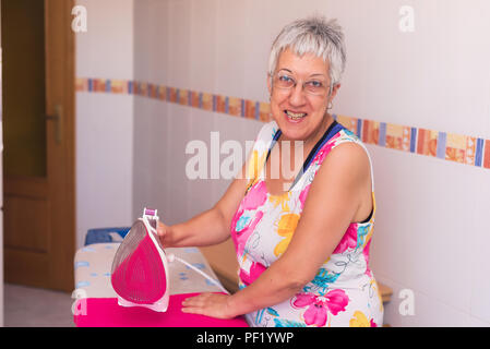 Senior donna la stiratura di panni Foto Stock