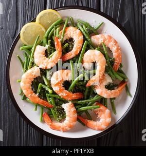 Frutti di mare insalata di gamberetti con fagioli verdi, formaggio e limone close-up su una piastra su un tavolo. vista in pianta da sopra Foto Stock