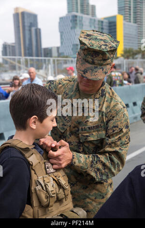 Lancia Cpl. Rutilo Jaramillo aiuta un bambino nel suo giubbotto  antiproiettile durante un tour di pubblico della USS ancoraggio (23 LPD), a  San Diego, Feb 18, 2016. Il tour ha mostrato al pubblico i tipi di  equipaggiamento e le condizioni di vita dei membri