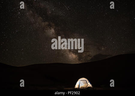 Via Lattea sollevandosi al di sopra di una piccola tenda. Foto Stock