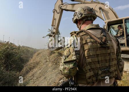 Il cap. Erik Blum orologi come Master Sgt. Thomas Ryan rimuove canne da 7 metri, profonda trincea a Kabul Air Wing, Afghanistan, 6 ott. 2016. Il treno, consulenza, assistenza Command-Air (TAAC-aria) ingegnere civile i consulenti hanno lavorato per cancellare un campo di canne in eccesso di 15 piedi di altezza. L'altezza della vegetazione era diventata una forza di protezione preoccupazione per il personale delle forze di sicurezza manning una voce del punto di controllo che non potrebbe più correttamente vedere oltre il campo. (U.S. Air Force foto di Tech. Sgt. Christopher Holmes) Foto Stock