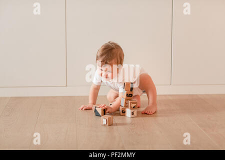 Piccolo Grazioso baby boy giocando con dei blocchi di legno in camera Foto Stock