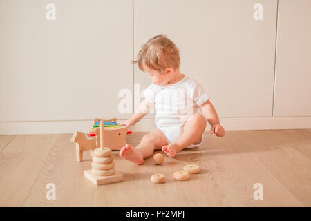 Piccolo Grazioso baby boy giocando con anelli di impilamento in camera Foto Stock