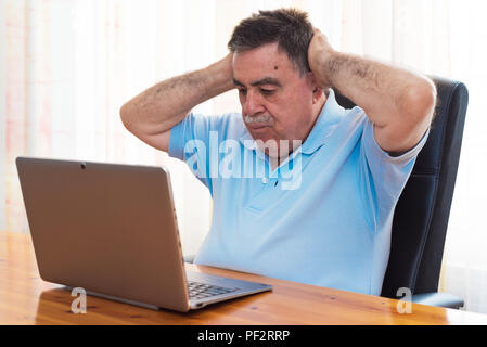 Sorpreso Senior uomo al lavoro con il computer portatile. Foto Stock