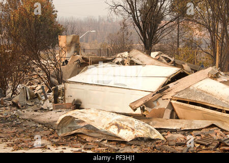 Home rasa al suolo, porta di garage allacciata e la posa di un heap dopo la recente wild fire fire storm in Redding, CA. Fumo e cenere in aria come Foto Stock