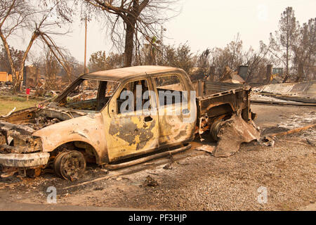 Carrello carbonizzati davanti casa rasa al suolo nel recente wild fire fire storm in Redding, California. Fumo e cenere in aria come il fuoco co Foto Stock