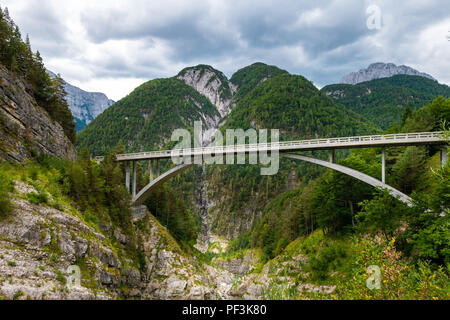 Ponte ad arcate su una montagna sulla gola del fiume nelle alpi europee con la montagna in background e cielo nuvoloso Foto Stock