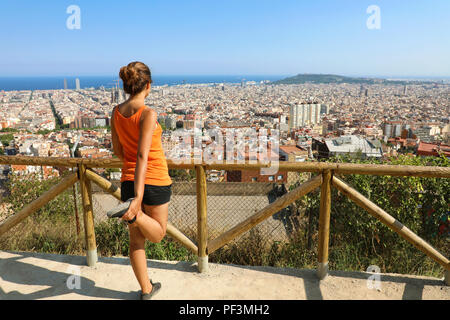 Emozionato attraente giovane donna in sportswear stretching godendo di paesaggio urbano di Barcellona al mattino. Buon umore, emozioni vere e uno stile di vita sano. Foto Stock