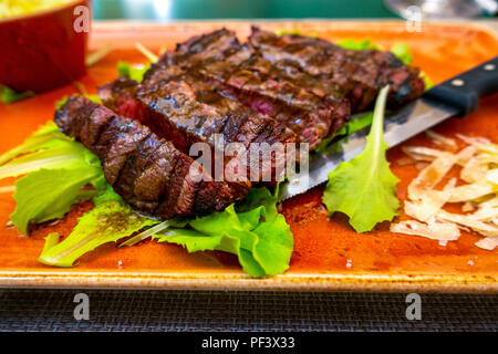 Italiano tradizionale di Tagliata di Manzo con parmigiano e insalata come close-up su una piastra Foto Stock