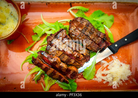 Italiano tradizionale di Tagliata di Manzo con parmigiano e insalata come close-up su una piastra Foto Stock