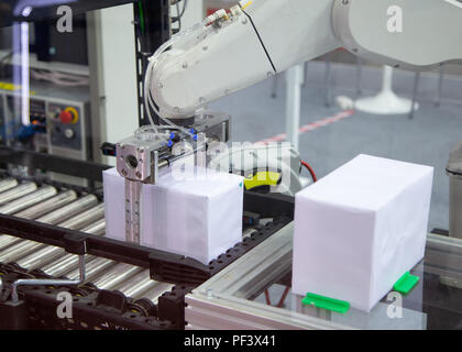 L'industria automatizzata di braccio di robot di carico e di scarico nella scatola di linea di produzione Foto Stock