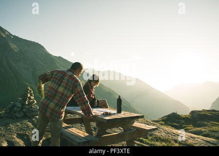 Gli escursionisti Coouple lettura mappa trekking sulla tavola in controluce, vista posteriore. Esplorazione e Avventura sulle Alpi. Foto Stock