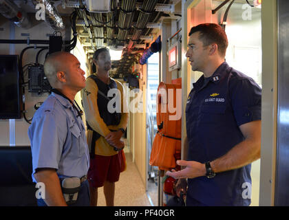 Lt. Ken Franklin (a destra), il comandante del guardacoste Oliver Berry (WPC 1124), discute le sue capacità con le Hawaii County Fire Department first responder Scott Shiroma (sinistra) e Hunter Henkel (centro) in Hilo, Hawaii, 14 agosto 2018. Il Oliver Berry era in Hilo di un programma comune di ricerca e salvataggio di esercizio tra la Guardia Costiera e Hawaii County primi responder. (U.S. Coast Guard foto di Sottufficiali di terza classe Matteo West/rilasciato) Foto Stock