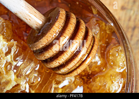 Miele di favo in una ciotola di vetro su sfondo di legno Foto Stock