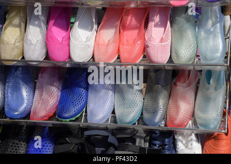 In gomma e silicone, sandali e scarpe da ginnastica sulla calzatura ripiano nel mercato. Foto Stock