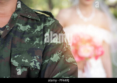 Un militare di Figura si erge davanti e la sposa sta dietro in una cerimonia di matrimonio. Foto Stock