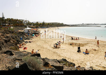 LANZAROTE, Spagna: 18 Aprile 2018: la splendida vista di Playa Dorada Beach con i bagnanti sulla sabbia, Lanzarote, Isole Canarie Foto Stock