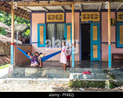 Ad Ambon, Indonesia - 11 Febbraio 2018: un gruppo di giovani ragazze indonesiane, in abiti colorati seduta sul hamak nel piccolo villaggio sull'isola, Foto Stock