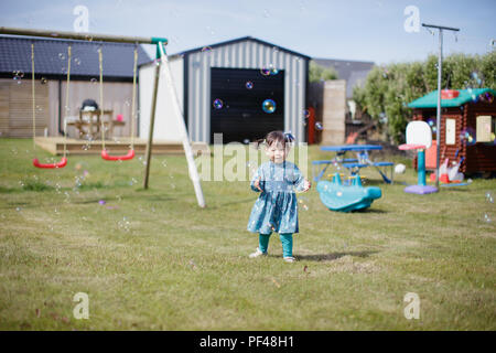 Bambina gioca bubble al giardino estivo Foto Stock