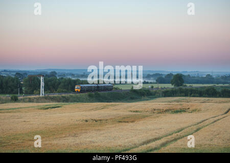 Un primo Great Western Railway classe 165 Turbo treno passa Culham al sorgere del sole in una nebbiosa mattina d'estate Foto Stock