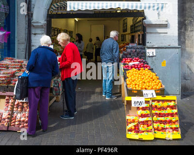 I clienti presso un fruttivendolo e fruiterers shop in un arco in Middlesbrough Town Center Foto Stock