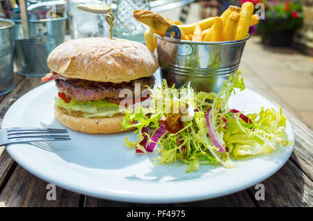 Café pranzo un primo hamburger di manzo con formaggio pancetta patate fritte e insalata mista Foto Stock