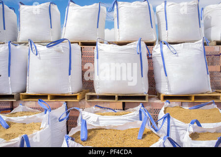 Pile di rafia grandi sacchi di sabbia impilate su pallet in legno con mattoni. Materiale di costruzione concept Foto Stock